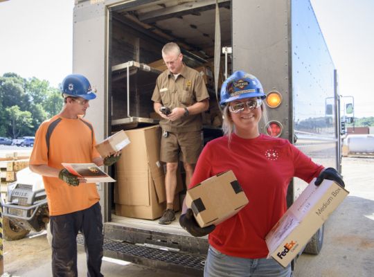 3 people unloading packages from a truck