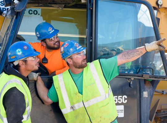 3 men in a construction vehicle