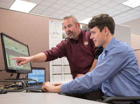 two men looking at a computer